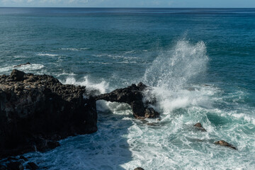 Scenic vista of waves breaking against the rocky shore along the Kaena Point trail on Oahu, Hawaii