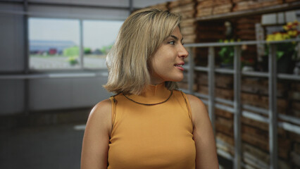 Woman wearing mustard top smiles showing shoulders in studio setting under soft light from large...