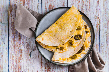 Close up of spicy quesadilla with cheese and jalapeno pepper on a plate on the table top view