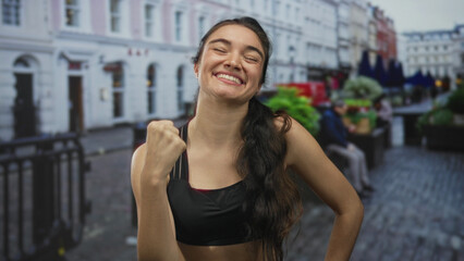 Woman counting on fingers by street benches amid pastel city buildings and potted plants in daylight; joy.