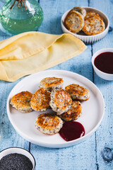 Small cottage cheese pancakes with poppy seeds on a plate on the table vertical view