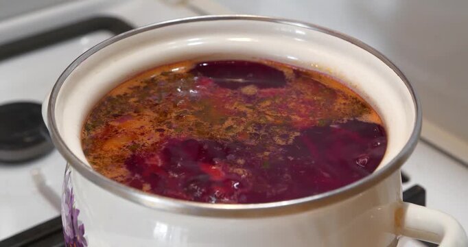 Red Ukrainian borscht is boiling in saucepan. National dish of Ukraine. Main first course of Ukrainian cuisine. Ukrainian borscht is cooked on gas stove. Cooking first courses