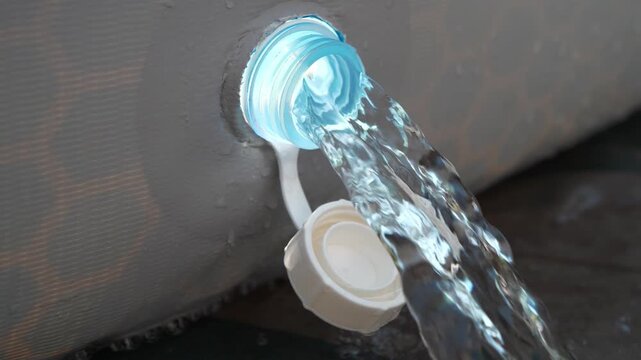 Water drains from frame pool. Video with sound. The noise of flowing water. Draining water from outdoor open-air swimming pool. Water is leaking from the tank