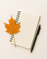 Autumn flat lay with maple leaf notebook and black pen on beige background
