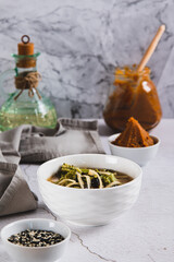 Delicious miso soup with noodles and broccoli in a bowl on the table vertical view
