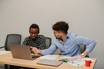 Diverse business team collaborating, discussing project on laptop