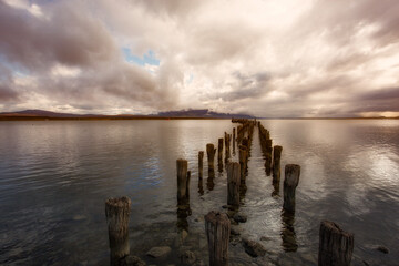 Obraz premium Dramatic Sun Rays Over Old Pier Pilings and Birds in Tierra del Fuego