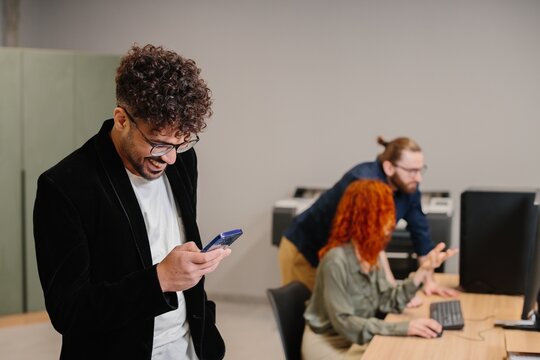 Young businessman laughing using smartphone in office