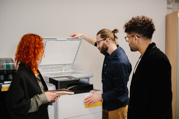 Office colleagues collaborating on printing documents using a copier machine