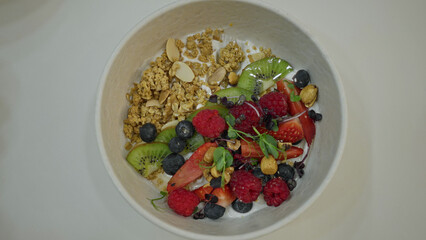 Bowl of fresh fruit and granola with colorful kiwis, strawberries, and raspberries, showcasing a healthy and delicious breakfast option in a vibrant and appetizing style.
