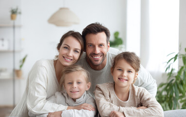 Fototapeta premium cheerful family with two happy kids and their parents embracing indoors, showing genuine connection, trust, well-being, parental care, and a cozy, home environment for perfect moment