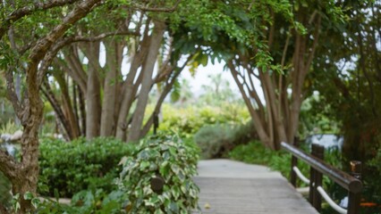 Blurred background showcasing a lush tropical resort with defocused greenery and a rustic wooden bridge, hinting at a serene, luxurious outdoor escape filled with natural beauty.