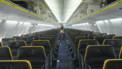 Fototapeta premium Airplane cabin blurred shallow interior background showing out of focus rows of leather seats and overhead bins; background copyspace backplate calm.