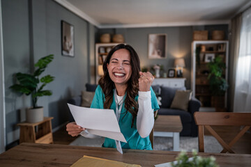 Happy young nurse celebrating good news, reading letter home