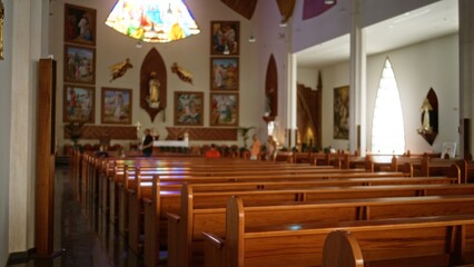 Church interior with shallow focus on wooden pews and defocused stained glass altar in the...