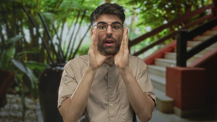 Man cups hands around mouth and shouts with clear voice in a modern building lobby by a staircase...