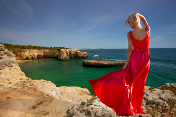 Woman in flowing red dress on ocean beach