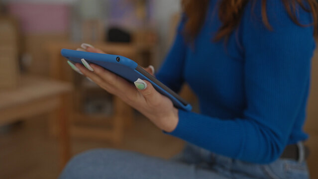 Woman using tablet in cozy new home living room with modern interior, highlighting relaxed tech integration into everyday life. - Powered by Adobe