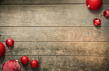 Top view red Christmas baubles on rustic wooden boards with copy space. Festive minimalist background for greetings, banners, marketing and design