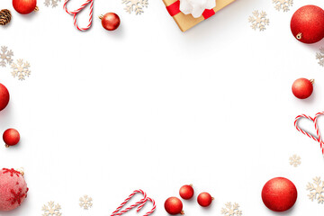 White background with Christmas decorations. Frame of red baubles, candy canes, gift and snowflakes top view