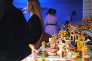 Elegant catering service showcasing an array of colorful snacks on a beautifully arranged table, with evening lighting creating a vibrant atmosphere for guests to enjoy