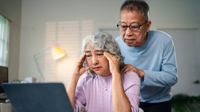 Senior Asian Couple Experiencing Financial Stress Looking at Laptop with Concern Anxiety Sadness and Support During Difficult Time