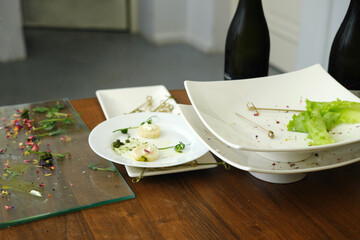 Elegant dining table with empty plates and remnants of gourmet dishes, showcasing fine dining experience and culinary artistry in a modern setting