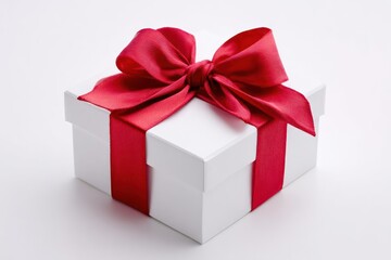 Obraz premium A beautifully wrapped white gift box adorned with a vibrant red satin ribbon and a large bow perfect for any occasion