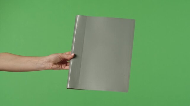 A woman hand holding a gray office folder with documents on a green chroma key background. Shot for designs related to office, business, education, and training.