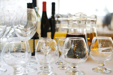 Collection of various glassware including wine glasses, tumblers, and a pitcher filled with beverages, elegantly arranged on a table, showcasing a refined dining experience