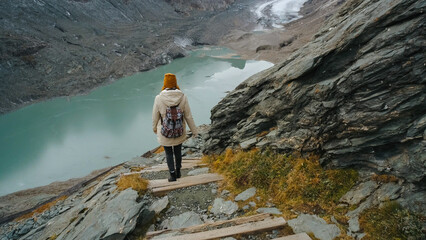 Hiking down a rocky trail towards a beautiful turquoise lake surrounded by mountains in a remote...