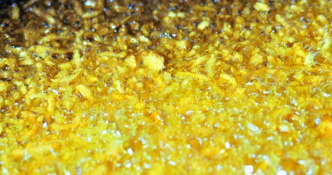 Yellow natural moving background. The process of overcooking carrots in vegetable oil. Bubbles of boiling oil swell and collapse.