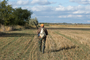 A hunter with a gun in camouflage clothing. A gentleman with a gun, medium shot, unrecognizable.