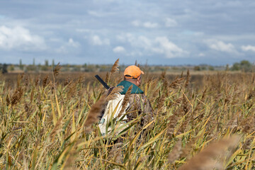 A hunter with a gun in camouflage clothing. A gentleman with a gun, medium shot, unrecognizable.