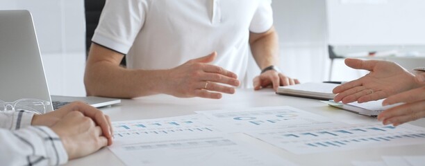 Professional business team reviewing financial data, collaborating over charts and graphs with laptop and pen in contemporary workplace, emphasizing strategic analysis and teamwork