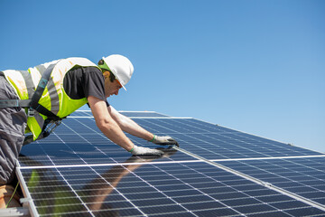 Workers install solar panels on a sunny day at a residential rooftop in an urban area