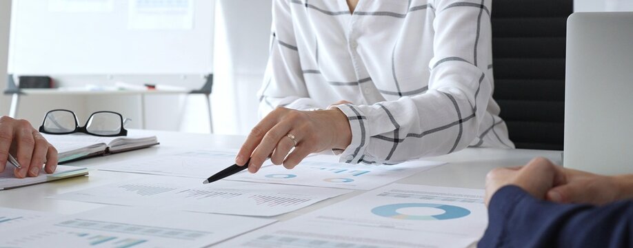 A business meeting with colleagues in a modern office where financial schedules, work planning, and reports are discussed in a team effort - Powered by Adobe