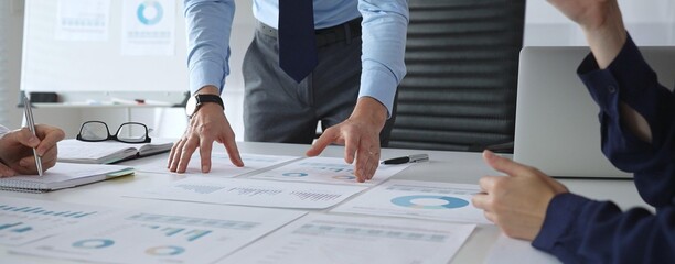 Business team analyzing financial charts and graphs during strategy meeting in modern office, focusing on corporate planning, data analysis, and decision making