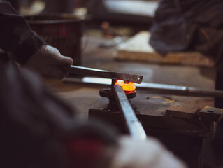 In the blacksmith's workshop, the blacksmith is leveling the red-hot metal with a hammer. A red-hot...