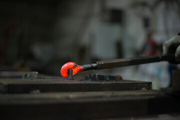 In the blacksmith's workshop, the blacksmith is leveling the red-hot metal with a hammer. A red-hot...