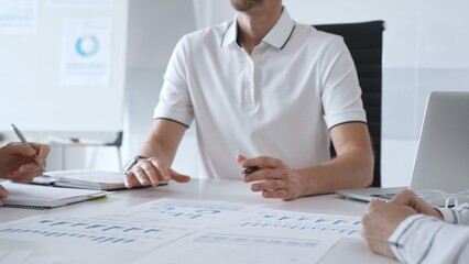 Professional business team reviewing financial data, collaborating over charts and graphs with laptop and pen in contemporary workplace, emphasizing strategic analysis and teamwork
