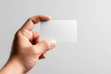 Fototapeta premium Human hand holding a blank translucent frosted business card against a neutral background for creative branding or identity design concepts