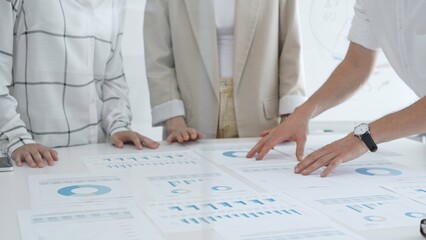 Business team analyzing financial charts and graphs, pointing at statistics and discussing data, working together on business project in modern office. Business people concept