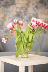 Vibrant bouquet of pink and white tulips arranged in a clear glass vase on a minimalist white table, enhancing the modern interior decor with a touch of nature