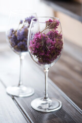 Elegant glasses filled with dried flowers in vibrant hues, placed on a rustic wooden surface, showcasing a unique interior decorating idea for home decor enthusiasts