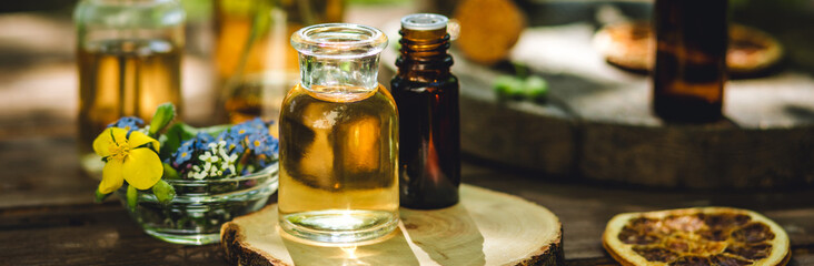 Banner. Concept of pure natural ingredients for cosmetic production. Alternative herbal medicine. Bottles of tincture, potion, organic essential oils, dry healthy herbs, floral extracts, wooden table