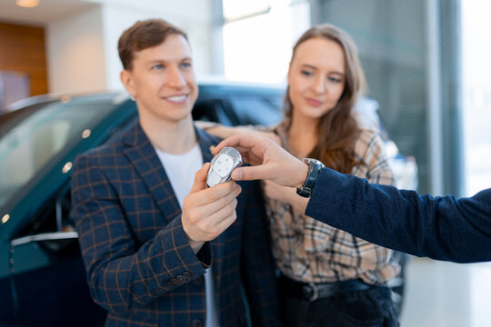 Happy millennial family receiving keys to new vehicle at car dealership
