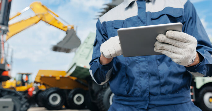 Worker use tablet computer for control work of drone trucks and excavator, AI modern technologies in industrial building site