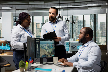Fototapeta premium Green tech company coworkers design advanced technology wind farm layouts and electric grids. Technicians in office brainstorming to upgrade eco friendly power lines and VAWT turbine designs