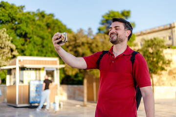 Man takes a selfie while enjoying a sunny day at a historic location with a smile